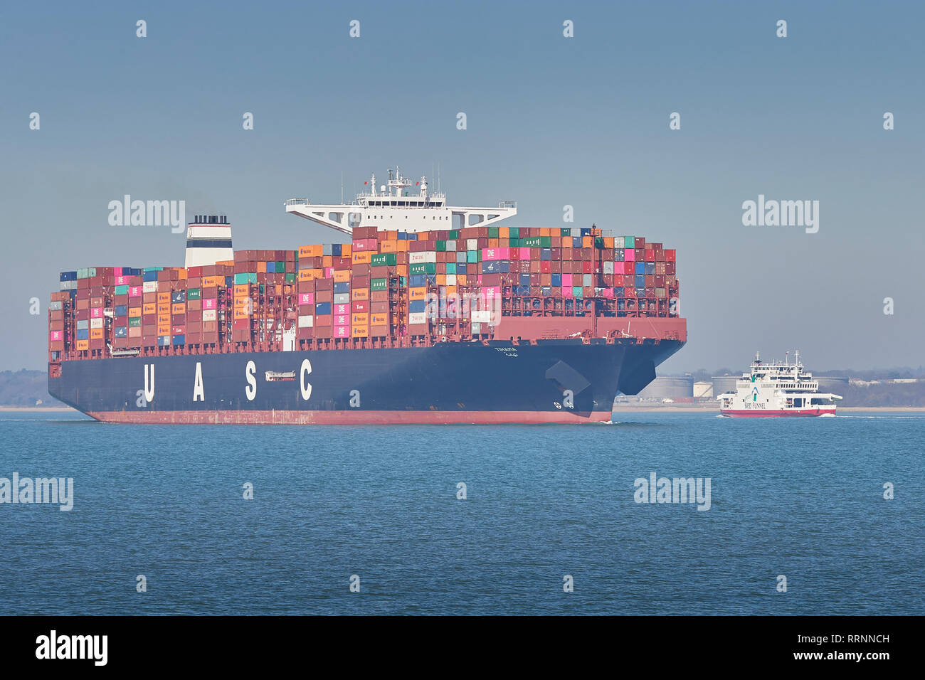 The 400 metre, Ultra-Large, Container Ship, TIHAMA, Passing A Red Funnel Car Ferry In The Southampton Harbour Deep Water Channel, Hampshire, UK. Stock Photo