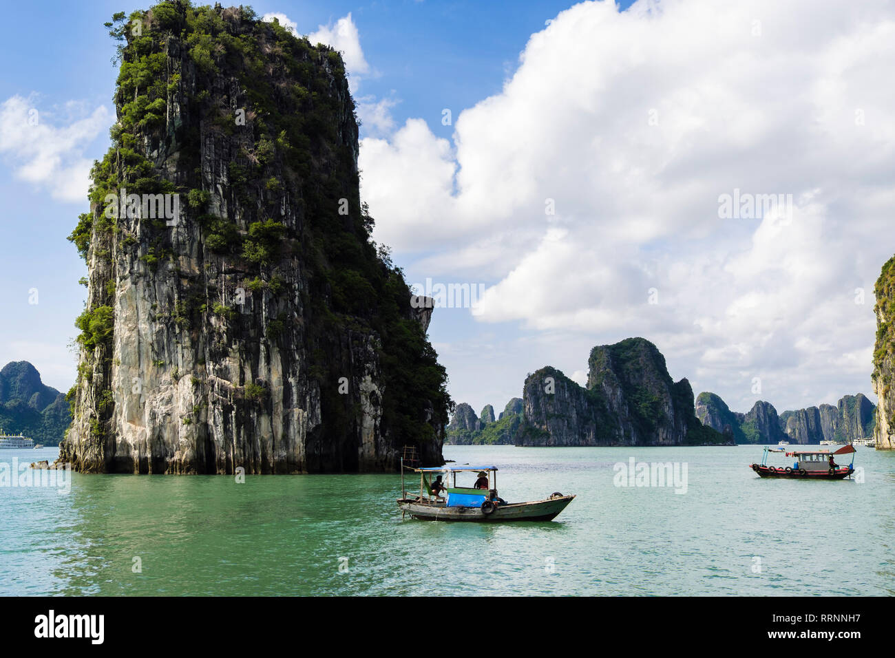 Traditional Vietnamese fishing boats sail between limestone rock islands in Ha Long Bay in South China Sea. Quảng Ninh, Vietnam, southeast Asia Stock Photo