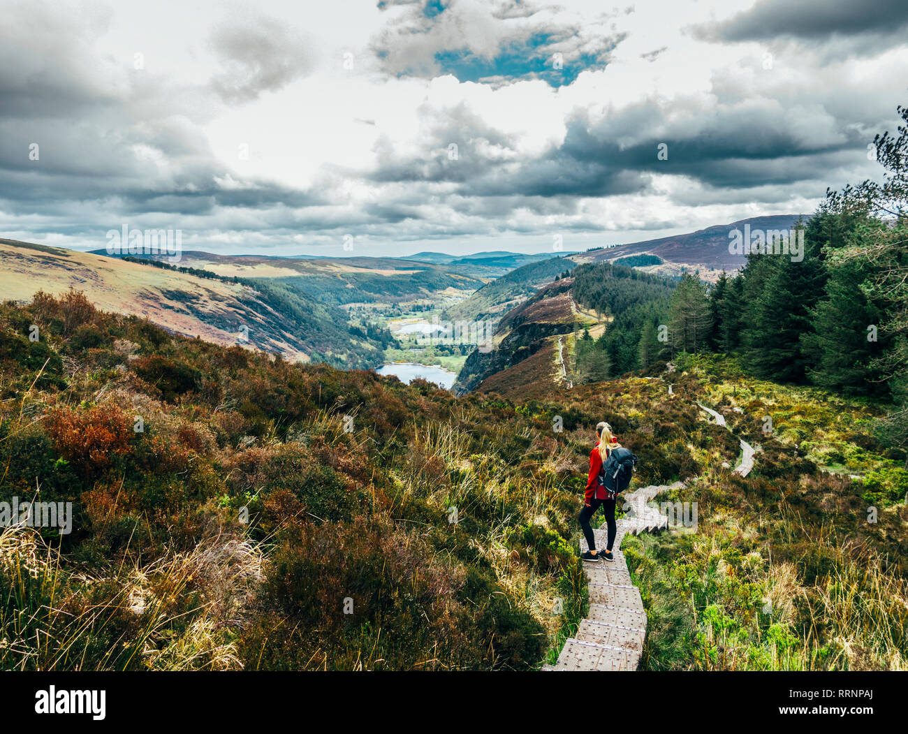Woman hiking along idyllic mountain path with scenic landscape view, Wicklow NP, Ireland Stock Photo