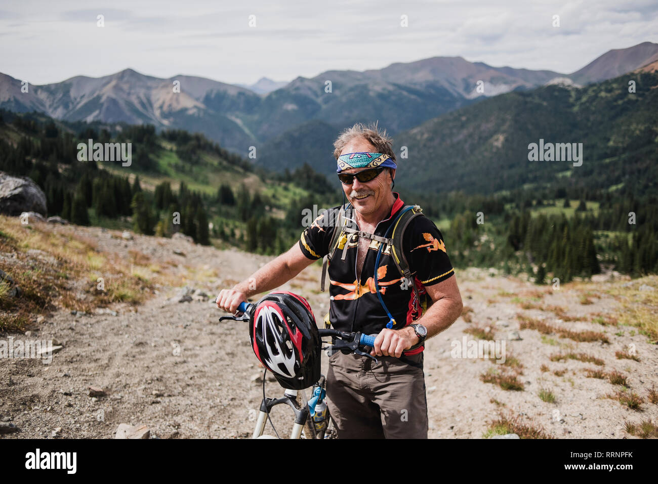 Portrait active senior man mountain biking in remote landscape, Chilcotin Mountains, British Columbia, Canada Stock Photo