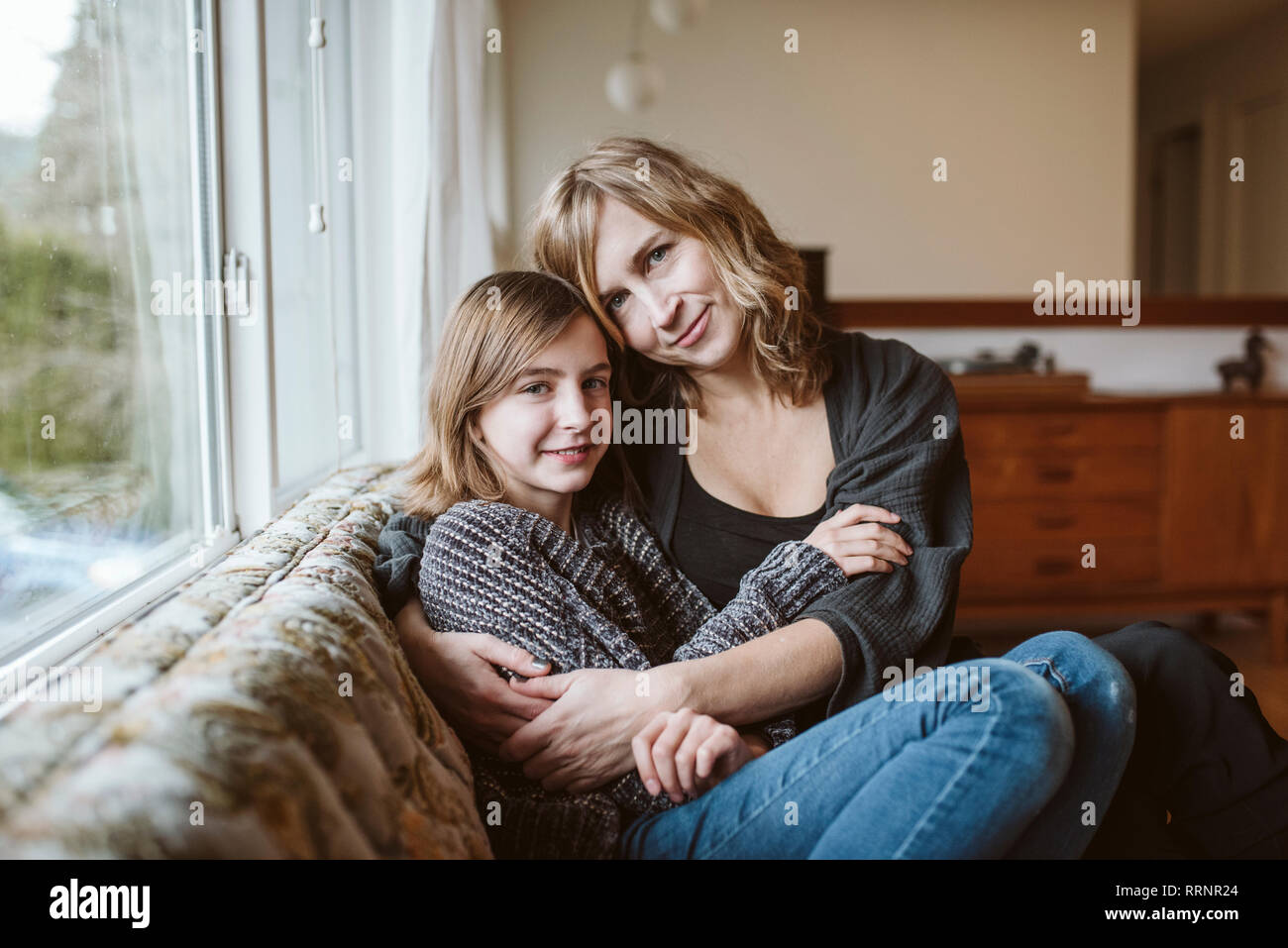 Portrait affectionate mother and daughter cuddling on living room sofa Stock Photo