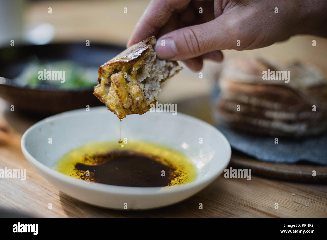 Close up hand dipping bread in olive oil and balsamic vinegar Stock Photo