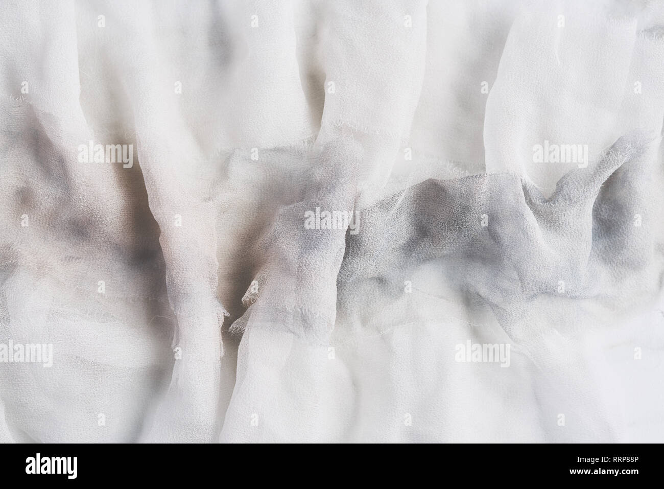White and gray wrinkled silk. Air folds. Silk fabric texture for background or design element. Thin tissue. Stock Photo
