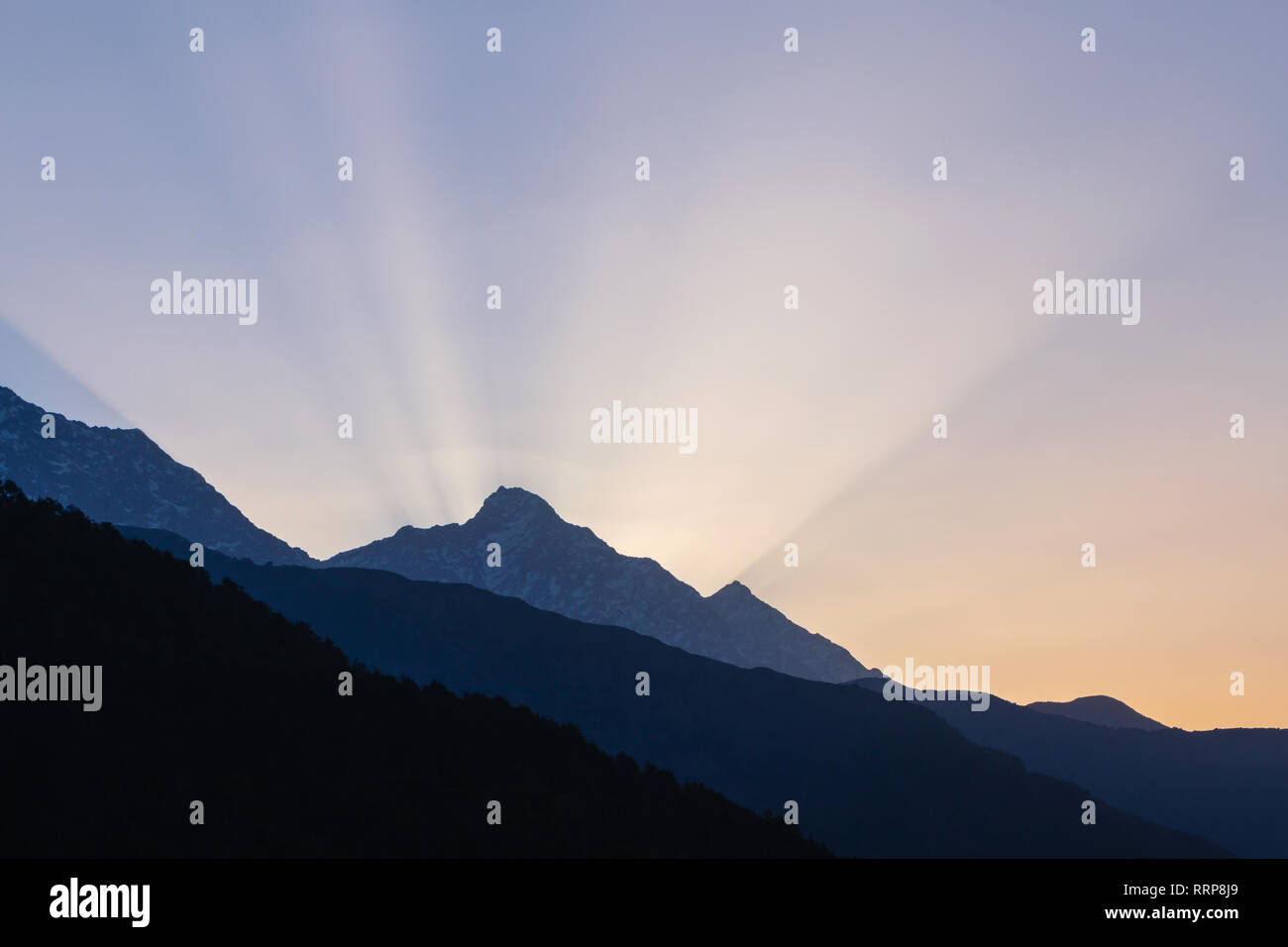 rays of rising sun behind mountain in Himalayas, India Stock Photo