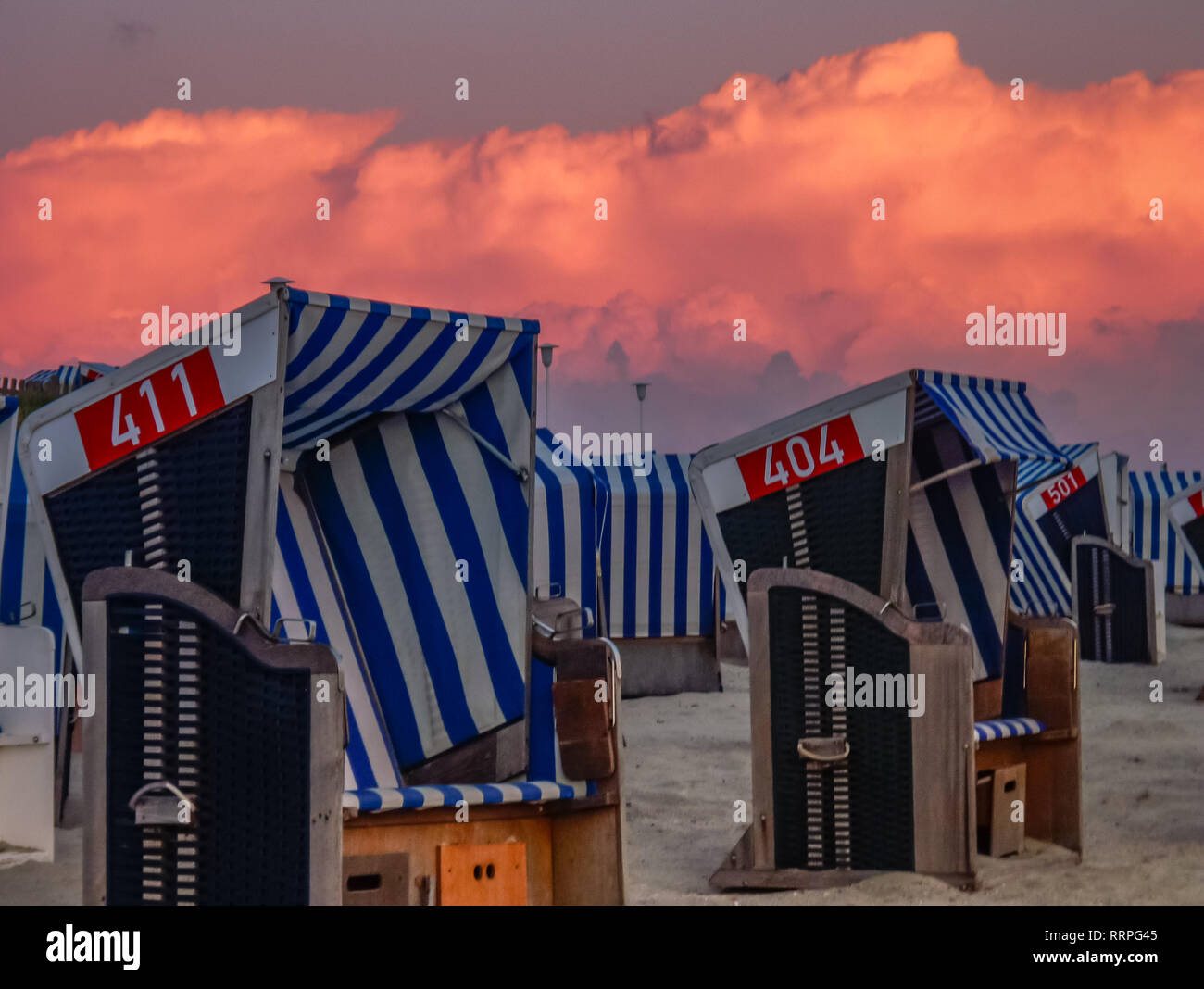 beach chairs in the sand. orange sunset calming mood travel scenery Norderney germany Stock Photo