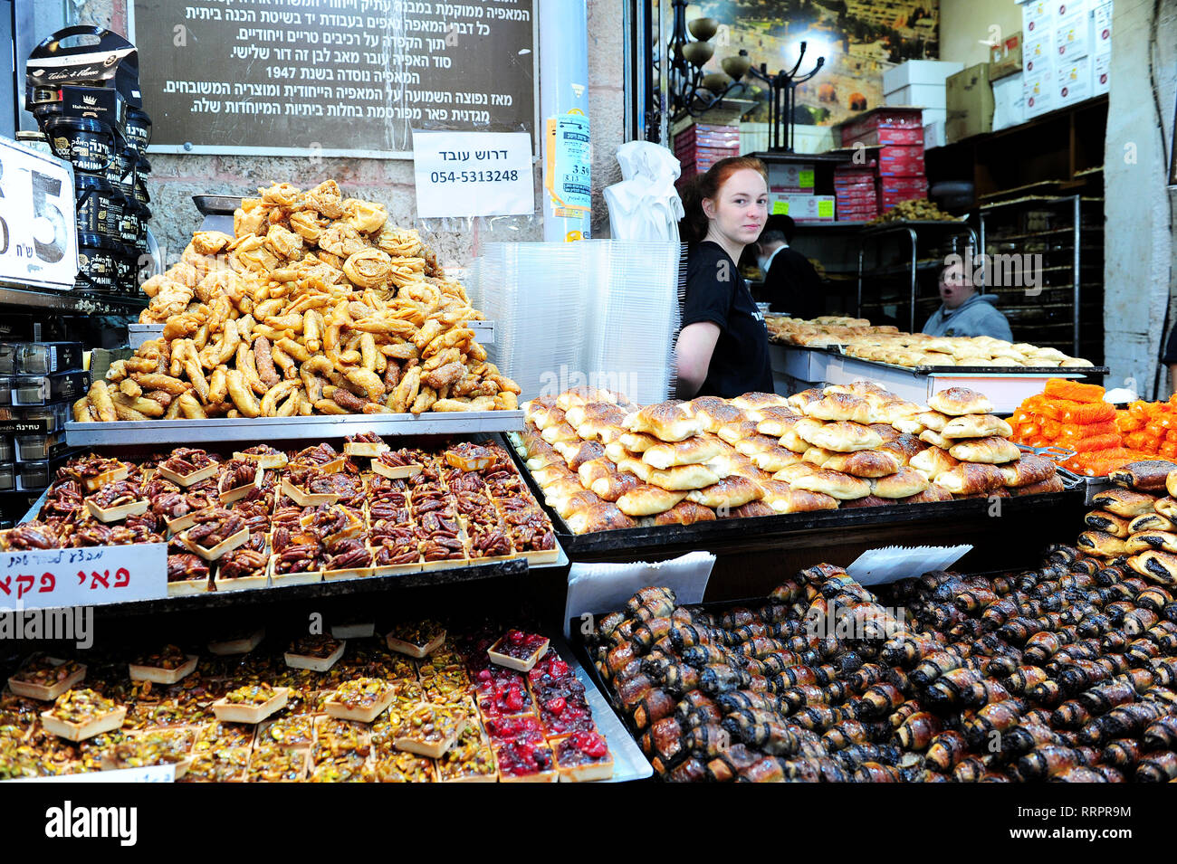A young female vendor portrayed behind her stall selling traditional Kosher treats at Yehuda Market, Jerusalem, Israel Stock Photo