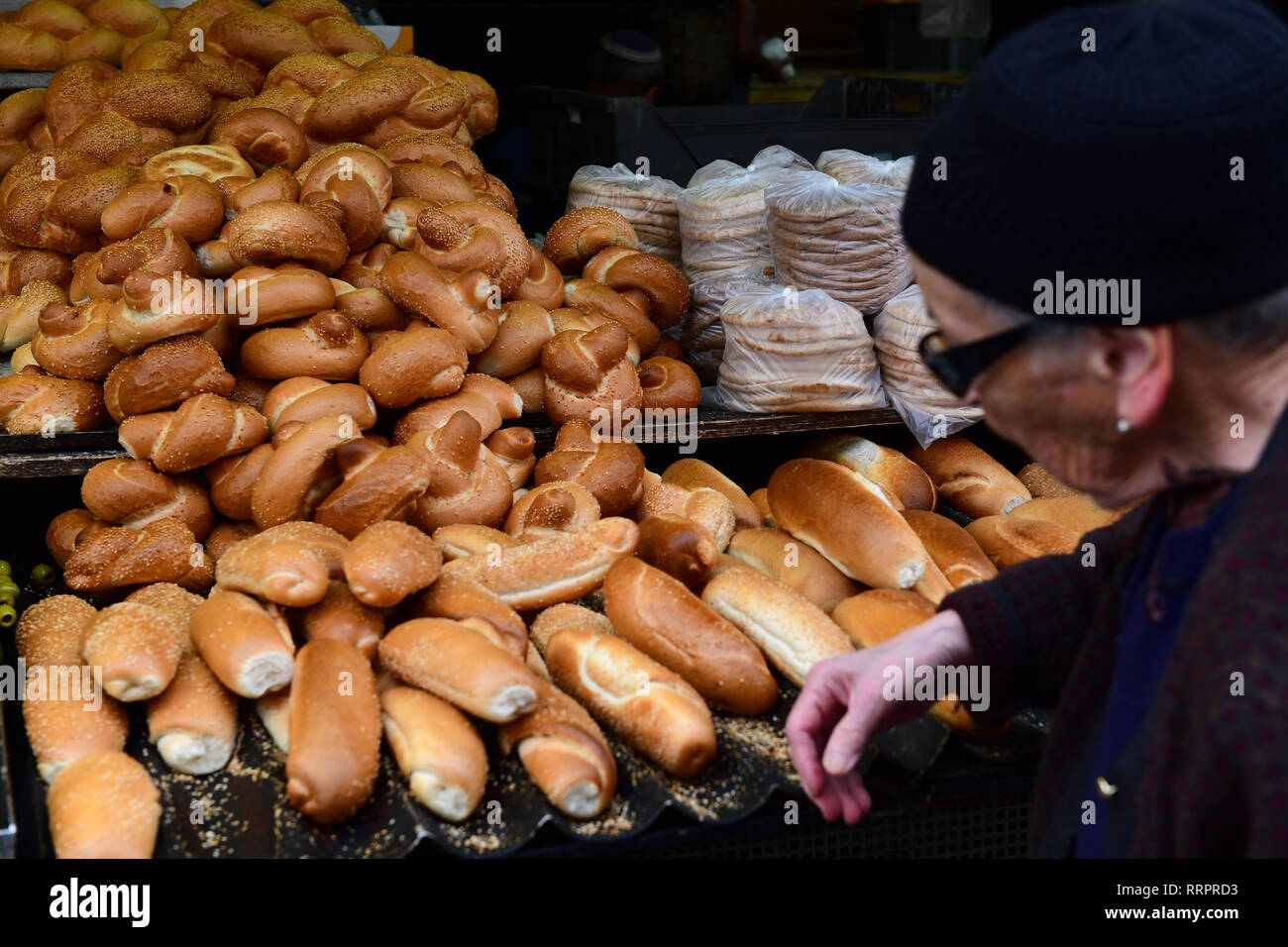 An elderly woman walks past a bread stall at Yehuda Market in Jerusalem, Israel Stock Photo