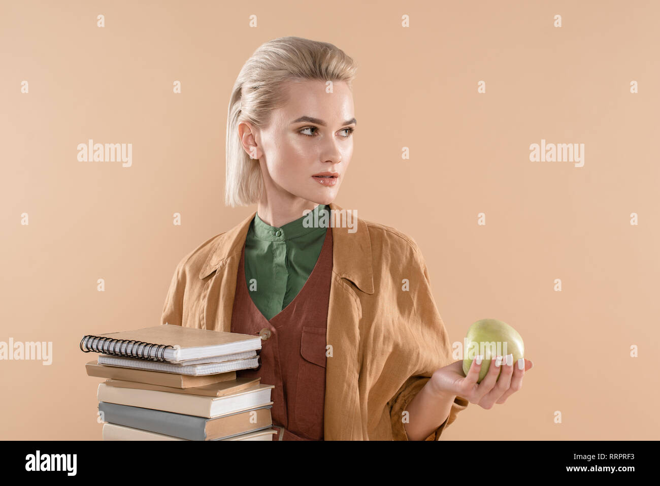 attractive girl holding books and green apple while standing in eco ...