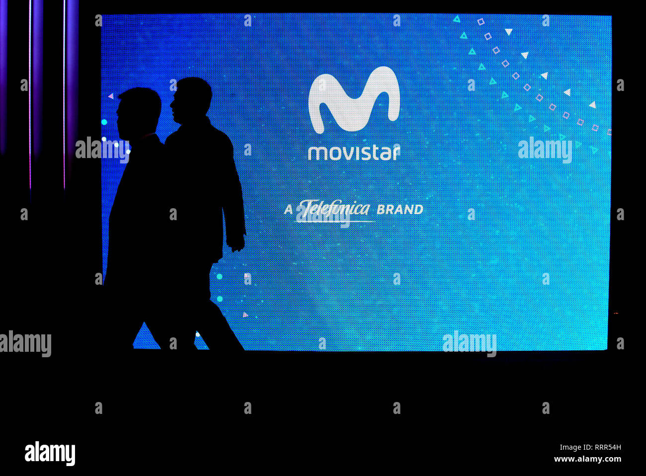 Two visitors are seen walking in front of the Movistar stand at the Mobile World Congress in Barcelona. Stock Photo