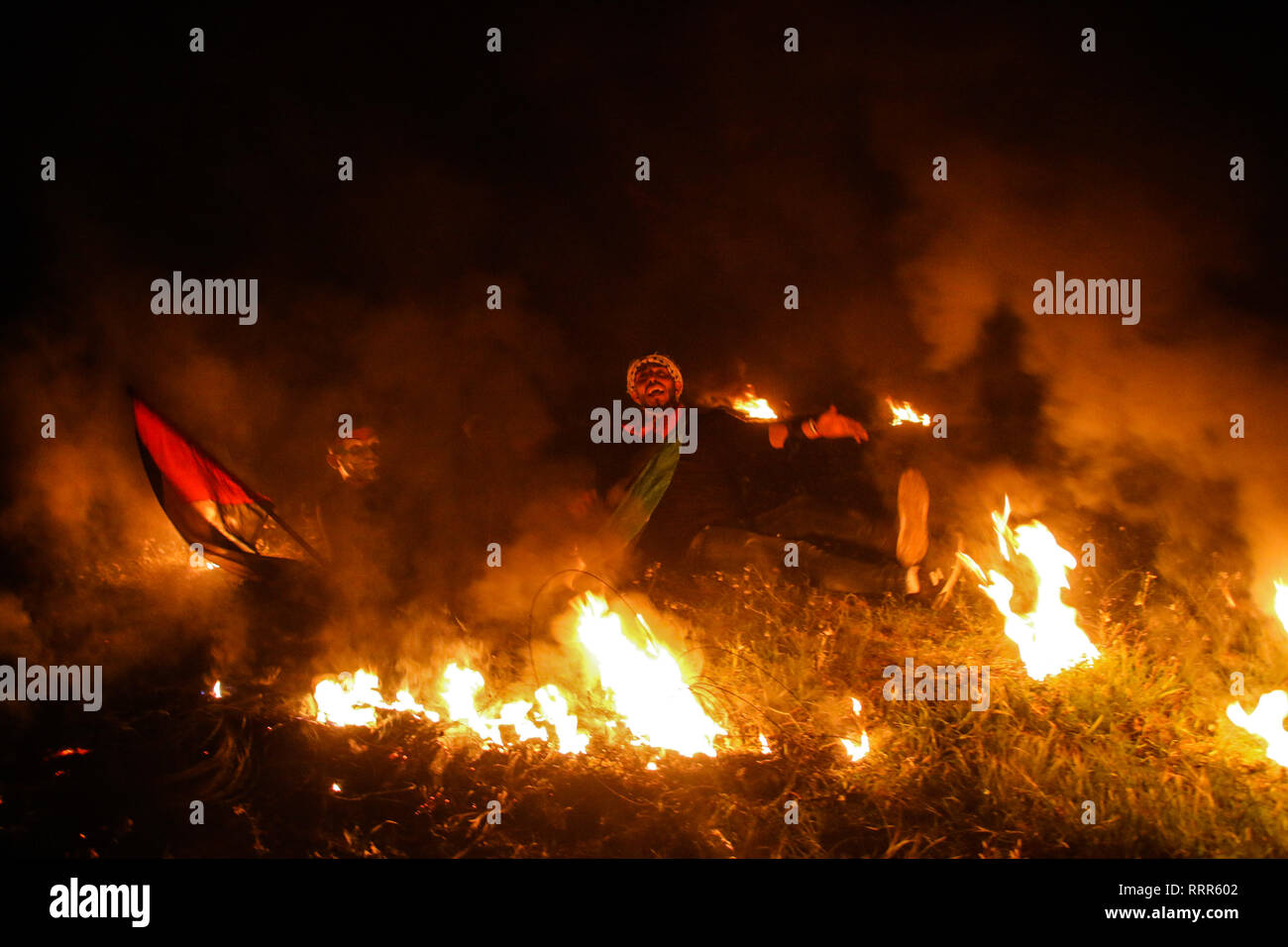 Gaza, Palestine. 26 February 2019. The 'Night Confusion'' unit hold a protest in the Malika area on the east of Gaza City, near the border with Israel, raising the Palestinian flags and setting tires on fire. Some Palestinians in Gaza known as the ''Night Confusion'' unit has begun organizing night demonstrations, during which they set tires on fire and chant slogans in protest against the tight Israeli siege on Gaza. Credit: ZUMA Press, Inc./Alamy Live News Stock Photo
