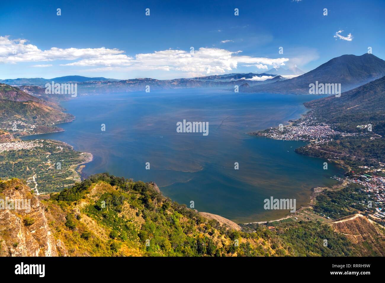 Aerial Landscape View of Blue Lake Atitlan surrounded by volcanoes in Guatemala Highlands with distant Panajachel and San Pedro Villages on Horizon Stock Photo