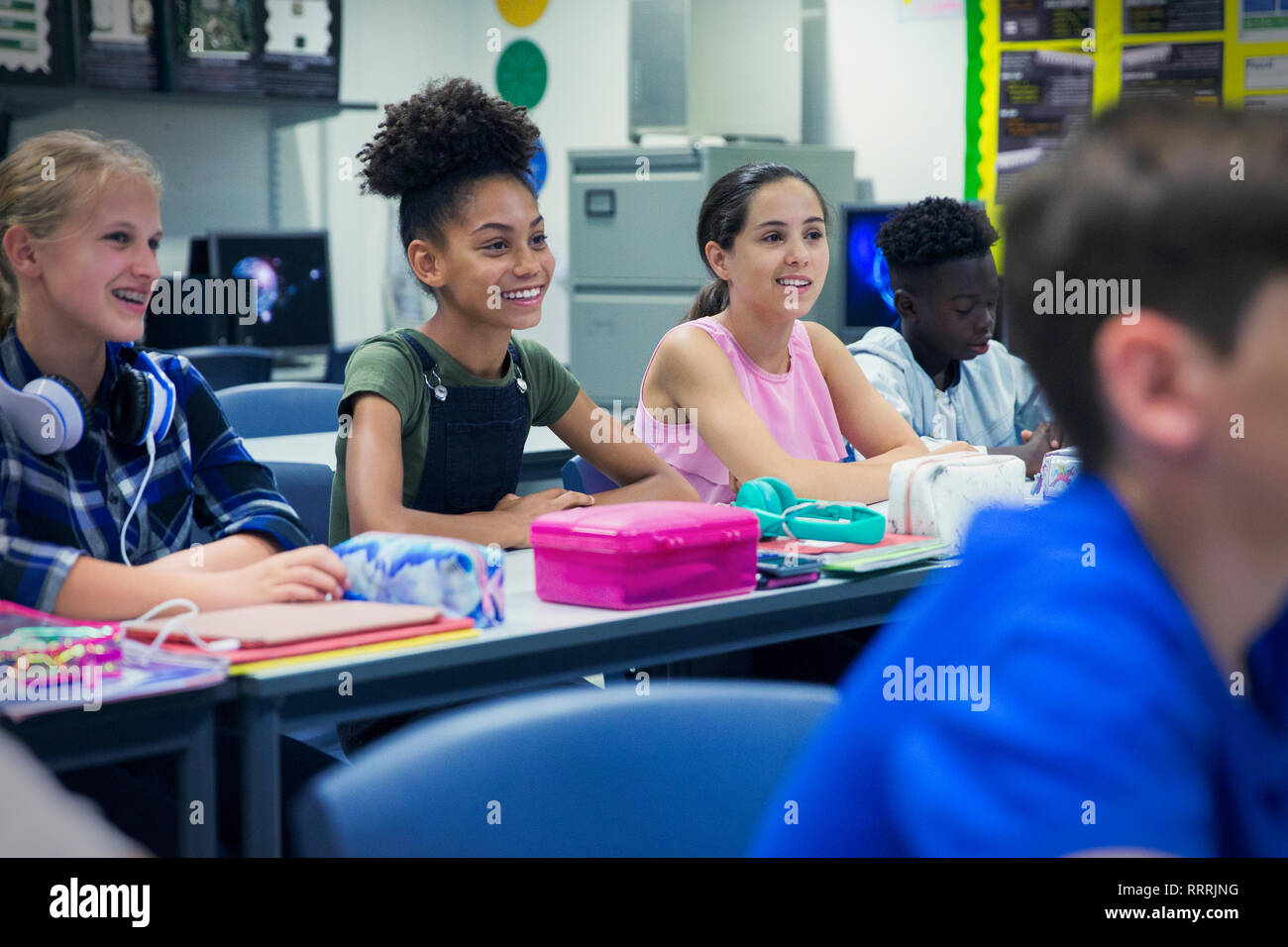 Smiling junior high school girl students at desk in classroom Stock Photo