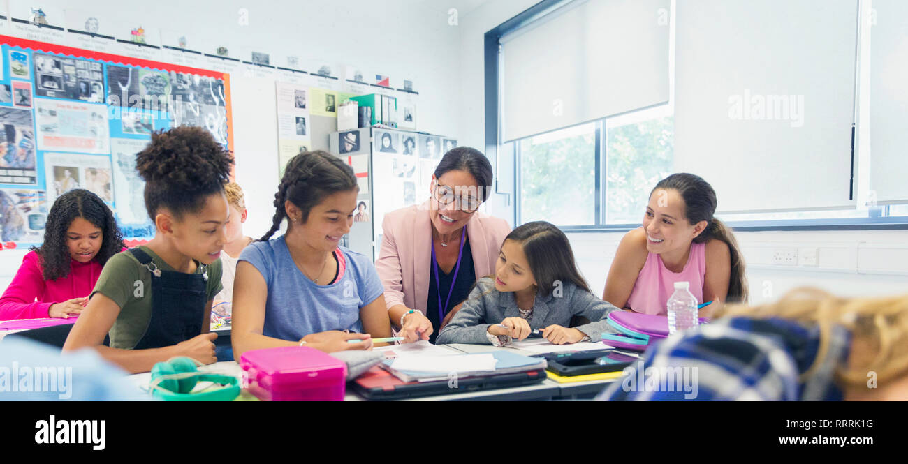 Female teacher and junior high school girl students at desk in classroom Stock Photo
