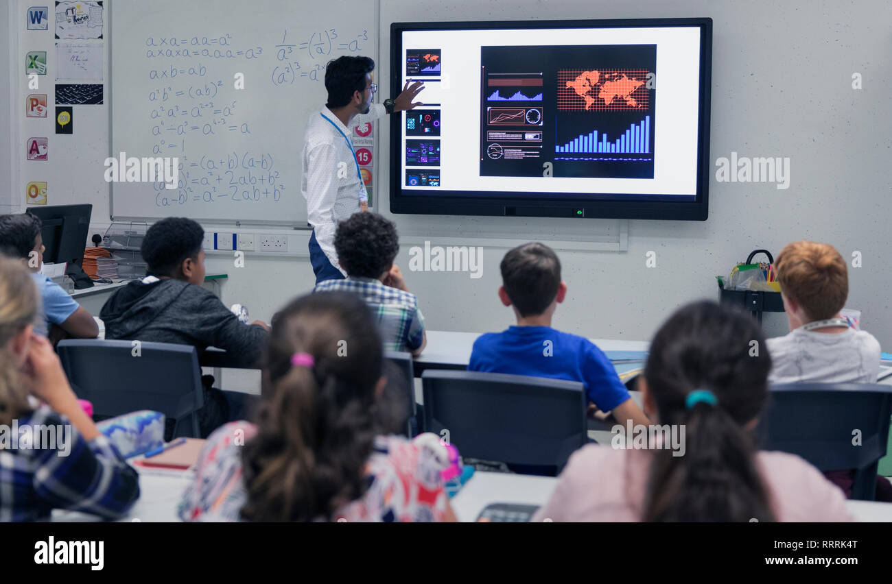 Male teacher leading lesson at touch screen television in classroom Stock Photo