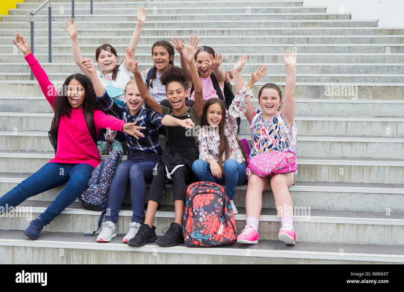 Portrait enthusiastic junior high girl students waving on steps Stock Photo