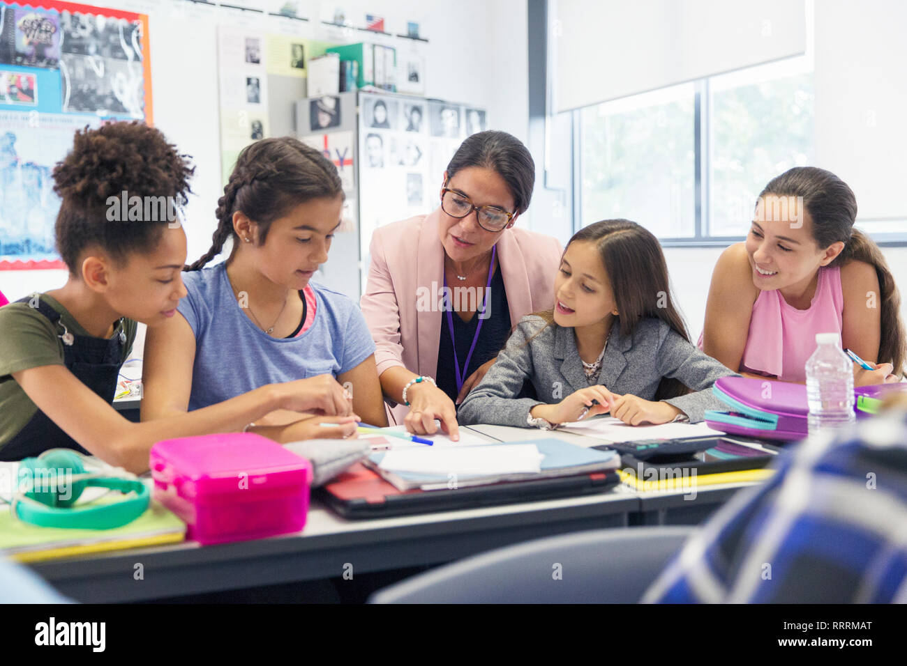 Female teacher and junior high school girl students studying at desk in classroom Stock Photo