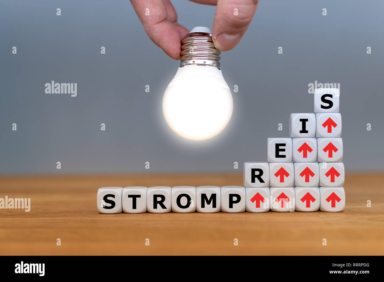 Symbol for increasing electricity rates. Dice form the German word 'Strompreis' ('electricity rate' in English) in front of a light bulb. Stock Photo