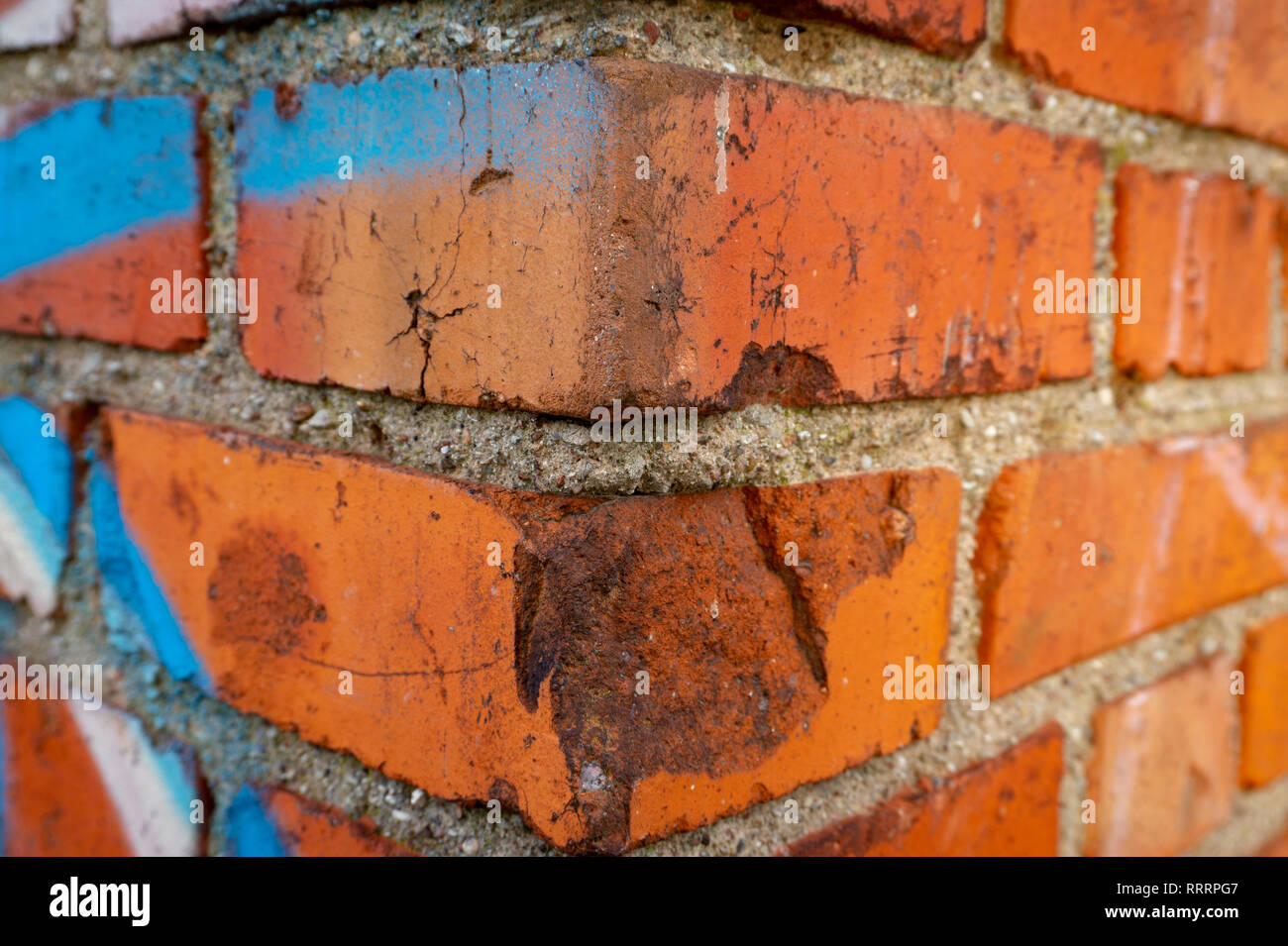 Corner of an old red brick wall with blue graffiti, viewed in close-up Stock Photo
