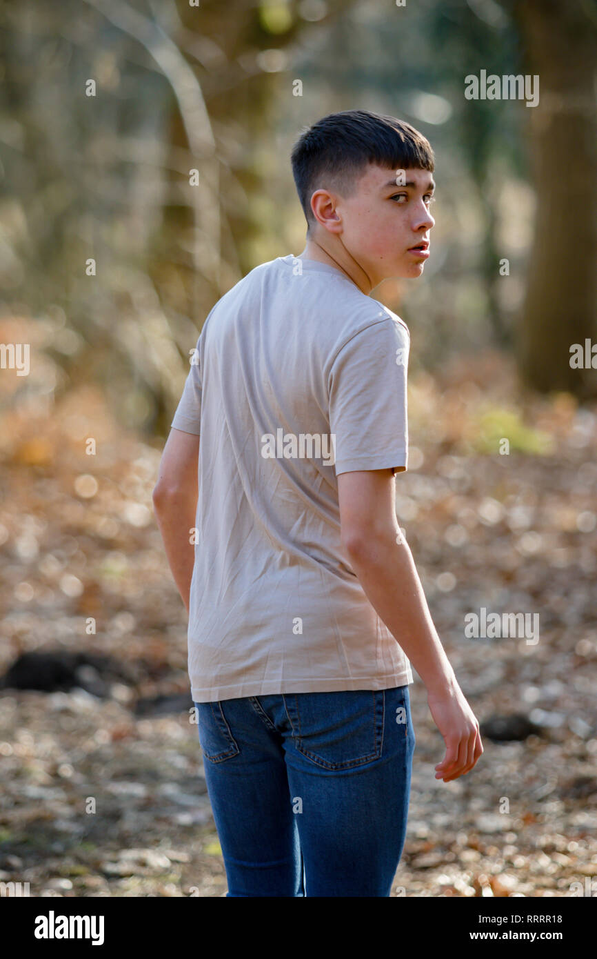 Scared or nervous teenage caucasian boy walking away through woodland ...