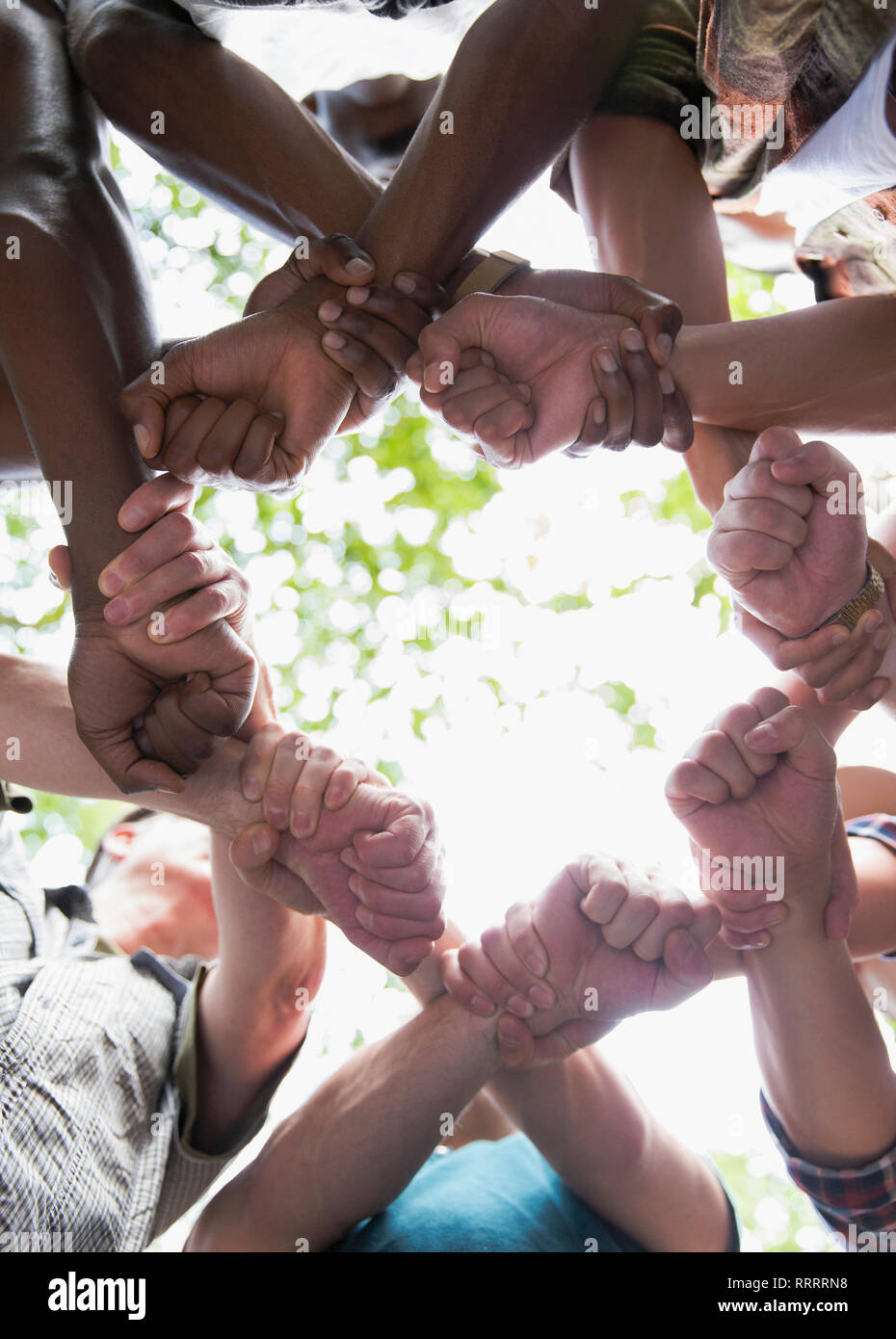 View from below mens group joining fists in solidarity Stock Photo