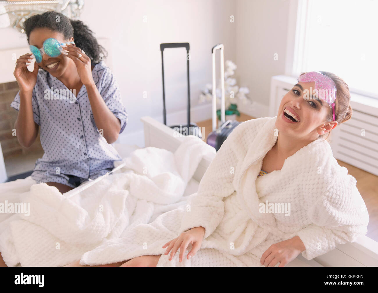 Portrait happy young women friends wearing eye masks in bedroom Stock