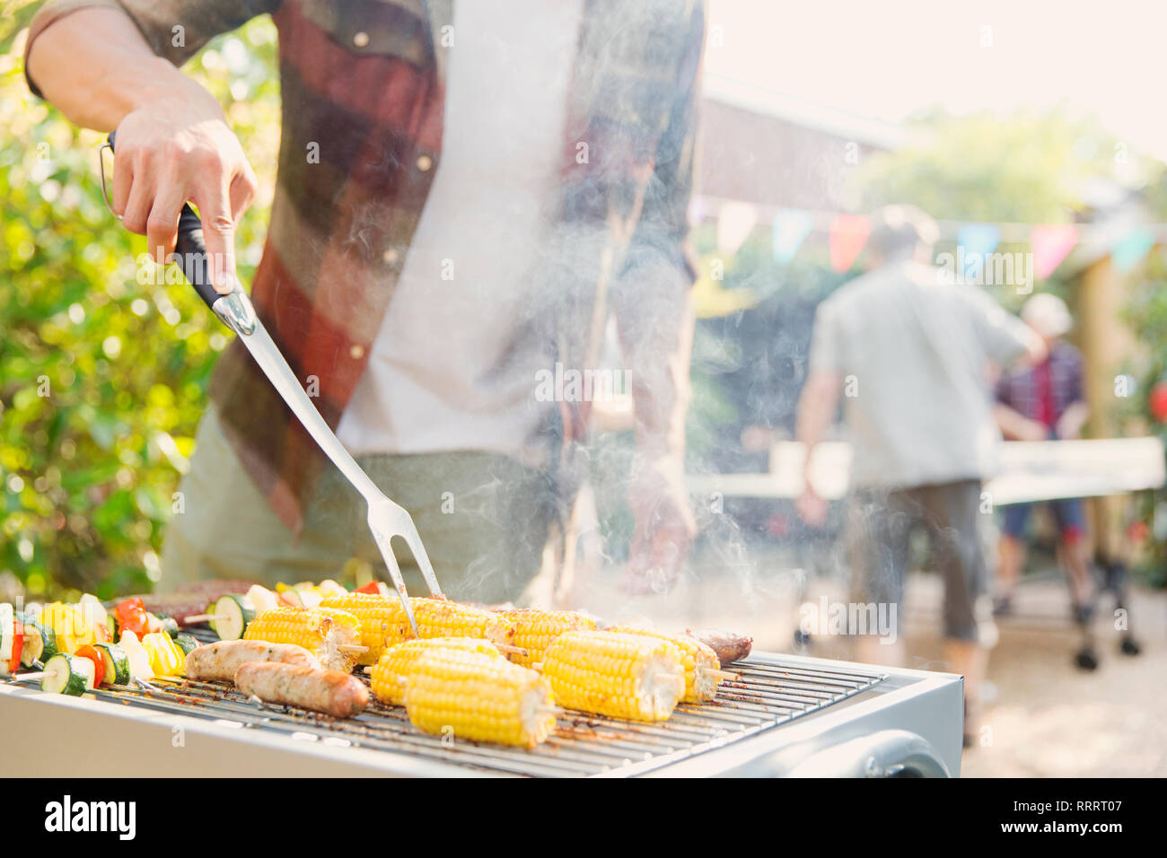 Man barbecuing corn, sausage and vegetable kebabs Stock Photo Alamy