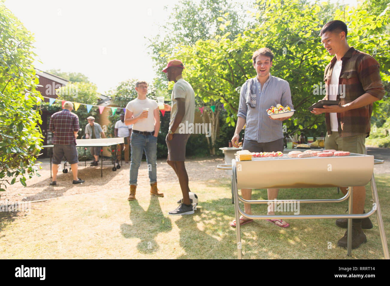 Male friends barbecuing in sunny summer backyard Stock Photo