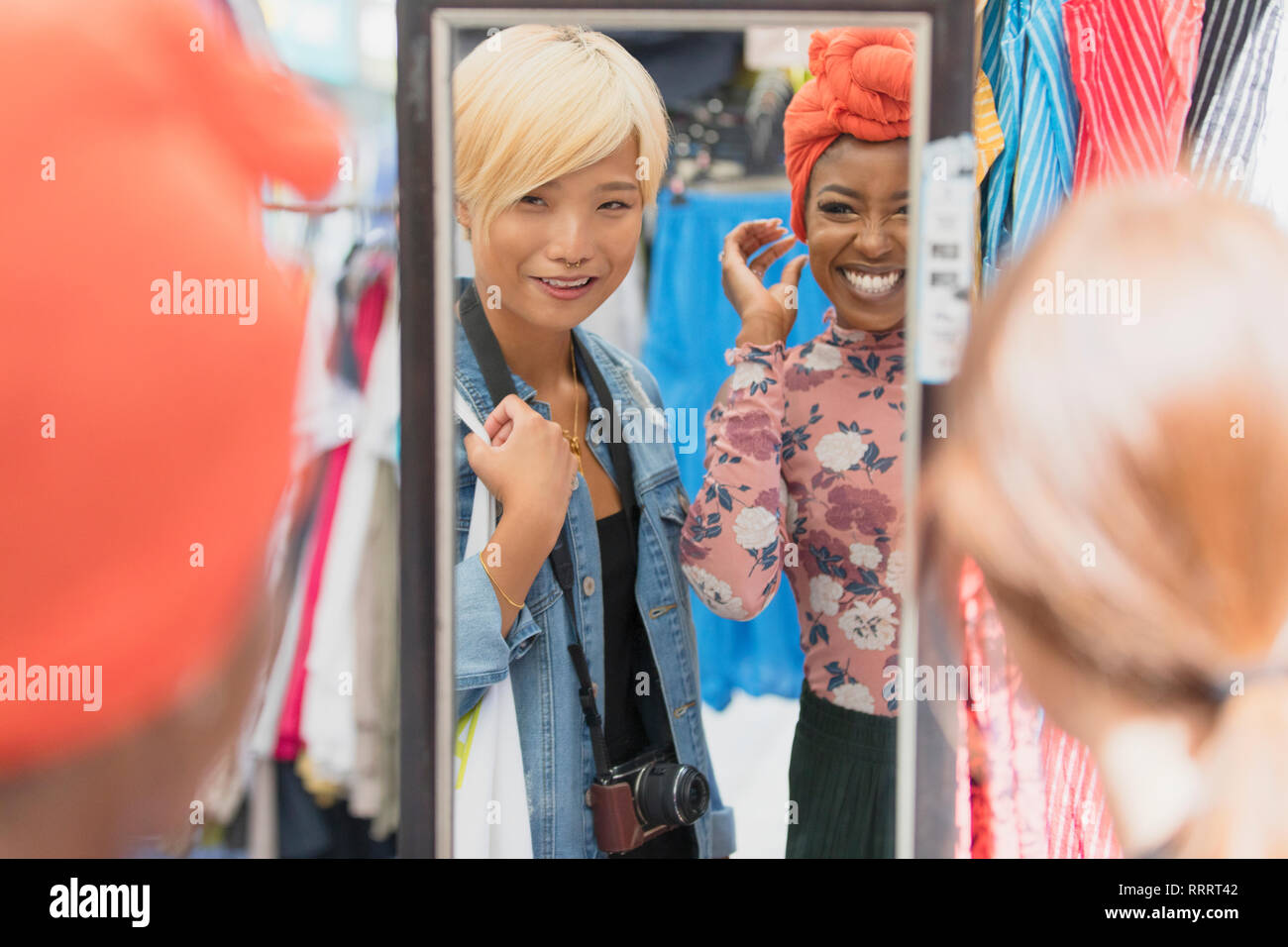 Young women friends shopping at mirror in clothing store Stock Photo