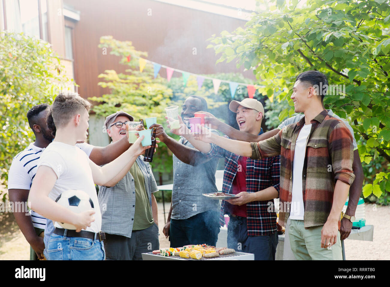 Happy male friends toasting drinks over barbecue grill in backyard Stock Photo