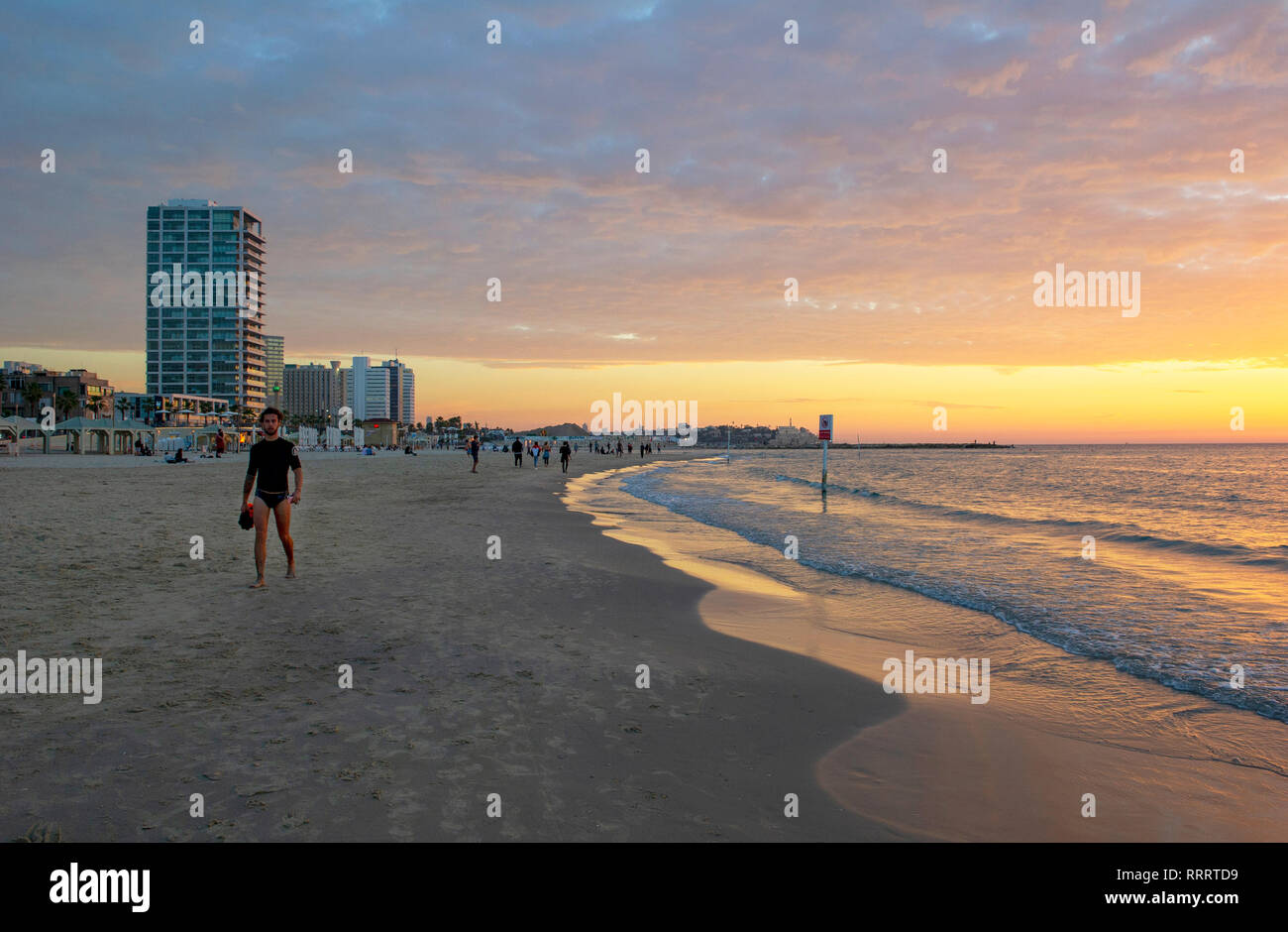 Young man waking along Tayelet, Tel Aviv's urban beach, at sunset, Tel Aviv, Israel Stock Photo