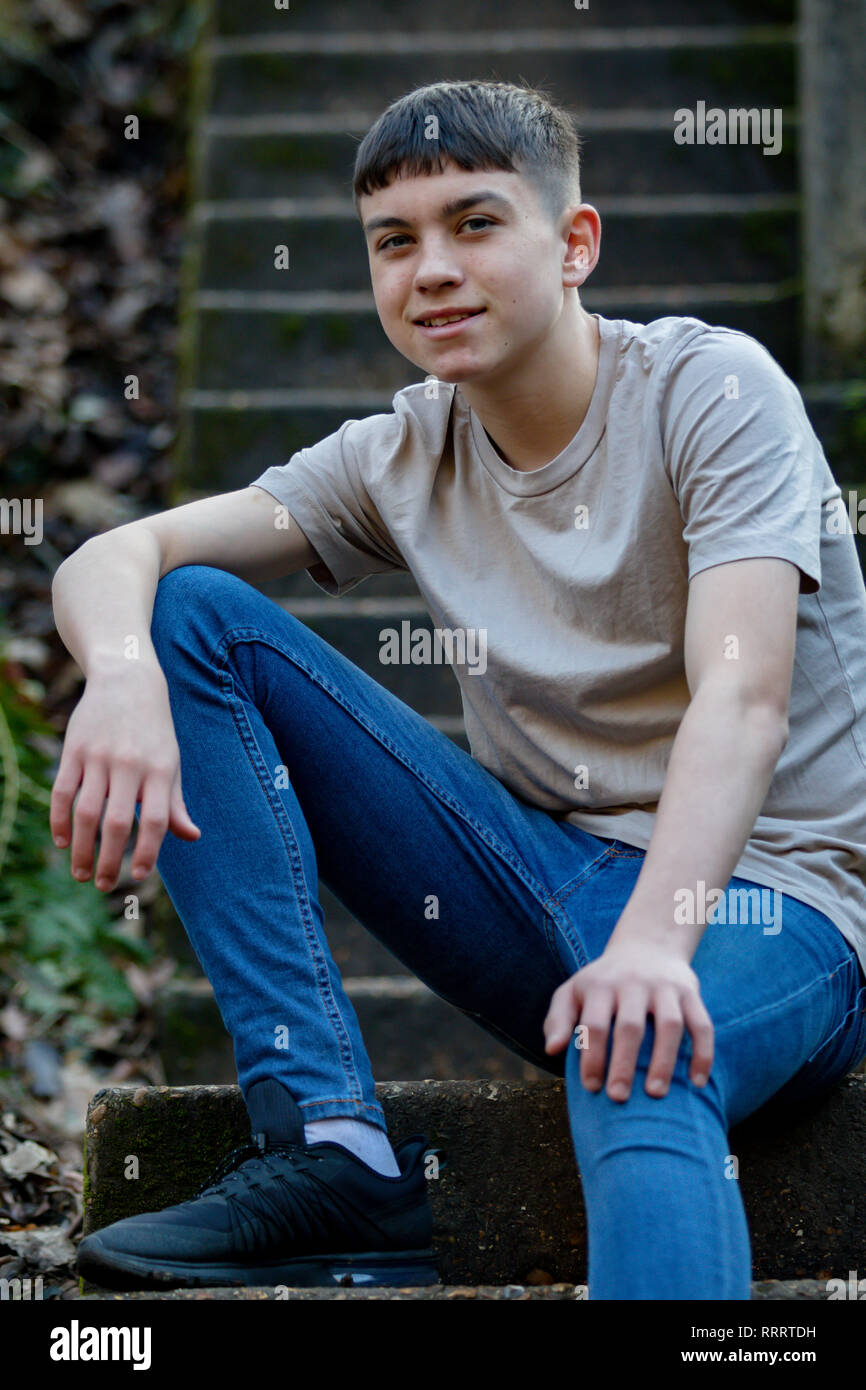 Portrait of a caucasian teenage boy sitting outside on concrete steps Stock Photo