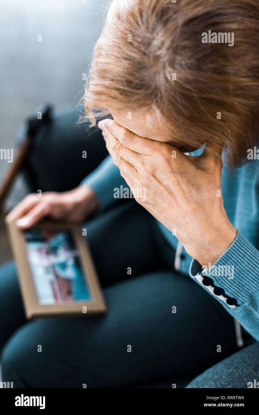 senior woman covering face with hand and crying while looking at ...