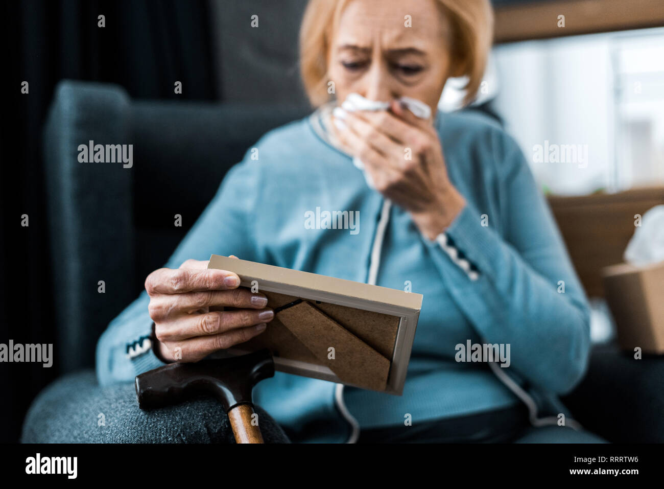 grieving senior woman crying and wiping face from tears with tissue