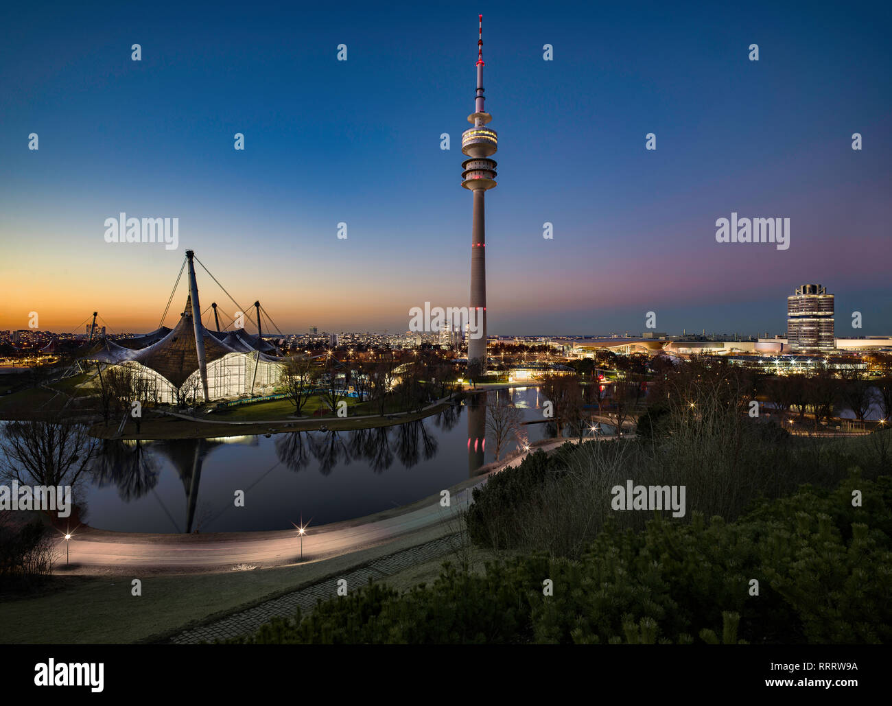 Beautiful Munich Olympic Park Skyline at sunset, stadium, 4 cylinder building, lake with relfection Stock Photo