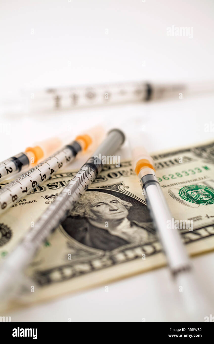 Closeup of medical syringes on top of a U.S. one dollar currency bank