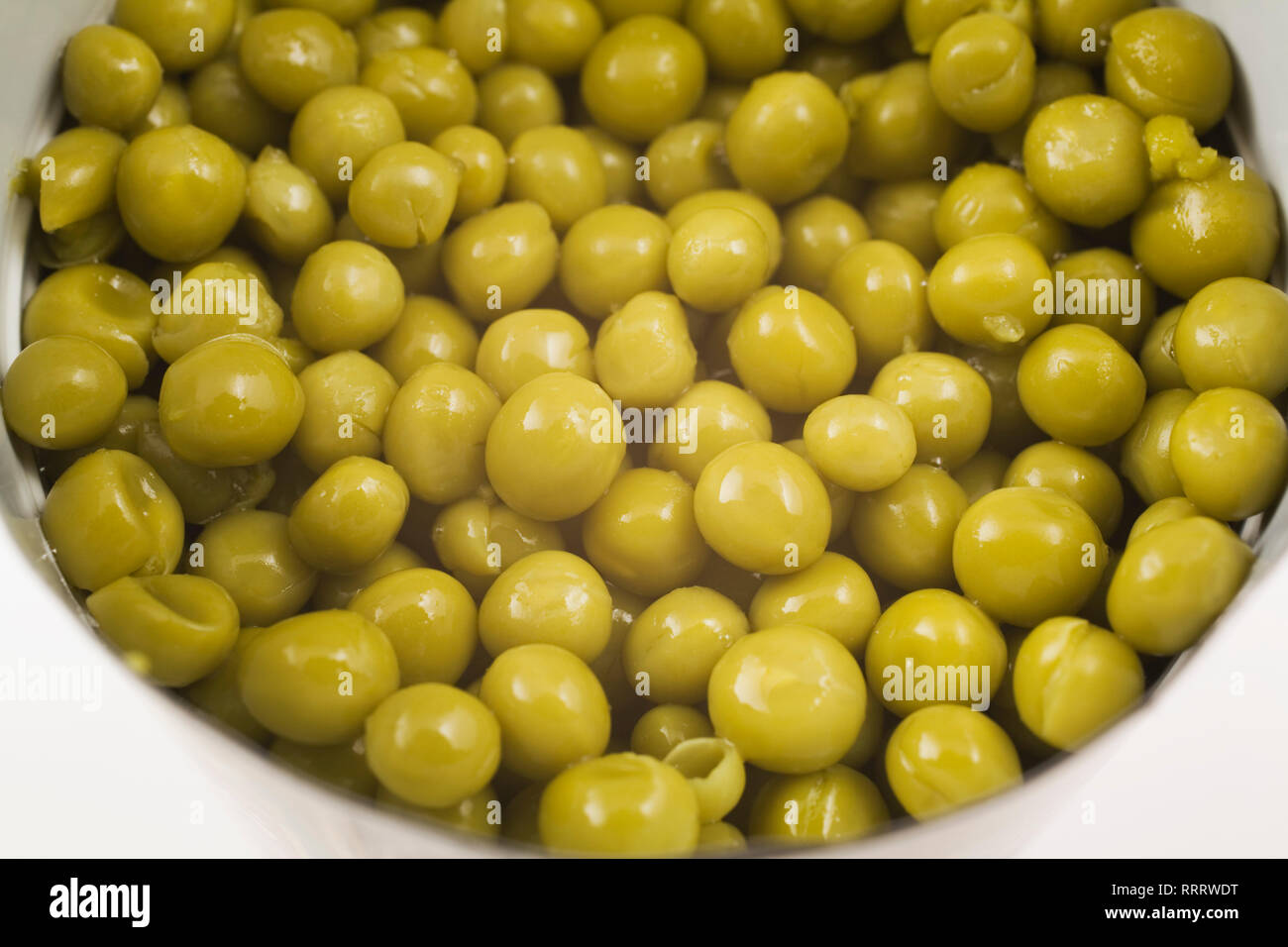 Closeup of green chickpeas in a opened tin can on white background