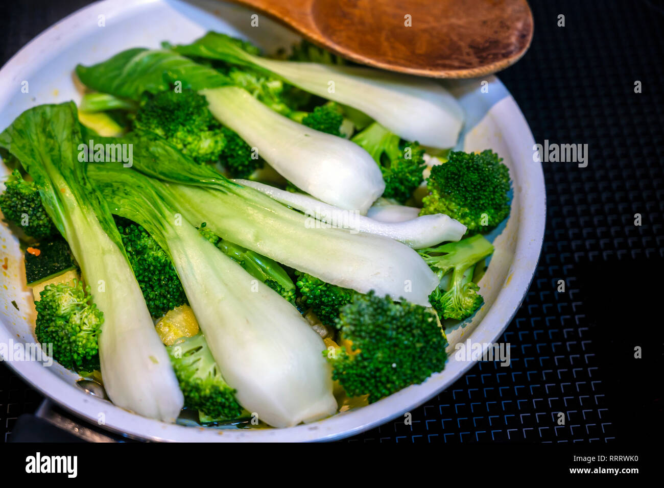 Long-leafed Cabbage with onion and broccoli stew in frying pan on an electric stove - dietary low-calorie natural organic dish that is good for your h Stock Photo