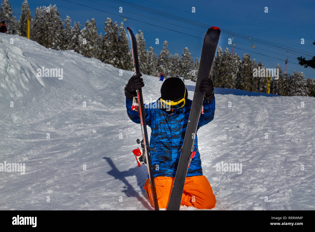 Young man sitting on snow and pair ski Stock Photo