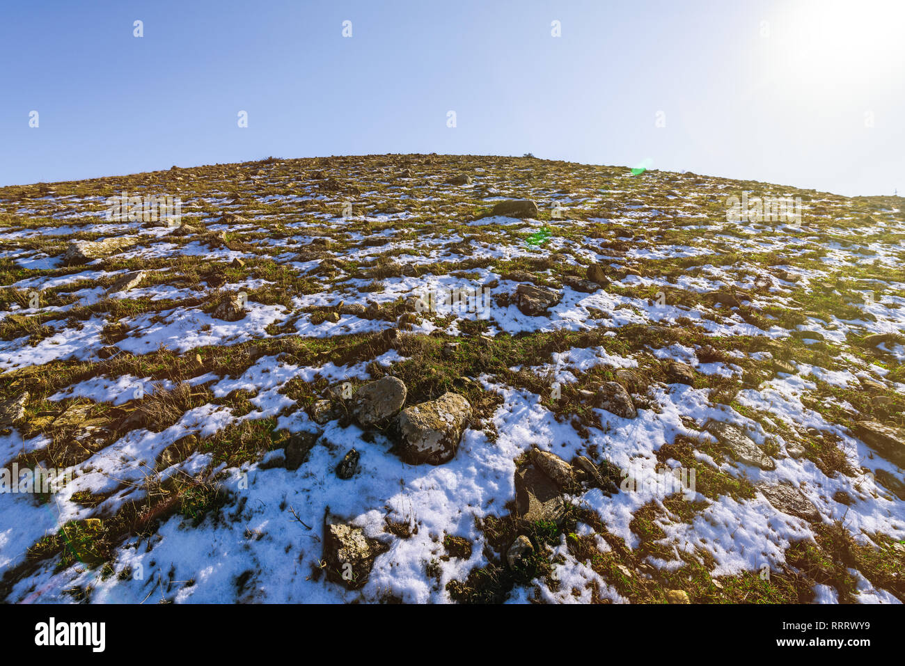Snowy alpine hill with sparse grass Stock Photo