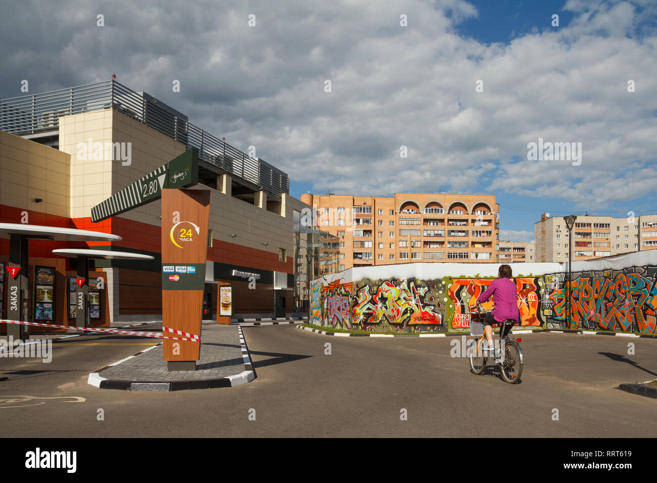 Dubna, Russia - Jul 21, 2014: Daytime street view of the city with a woman riding bike. Stock Photo
