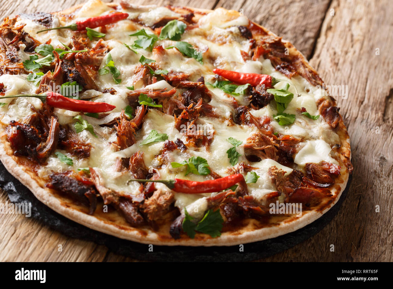 Homemade pizza with pulled pork, cheese, pepper and barbecue sauce close-up on the table. horizontal, rustic style Stock Photo