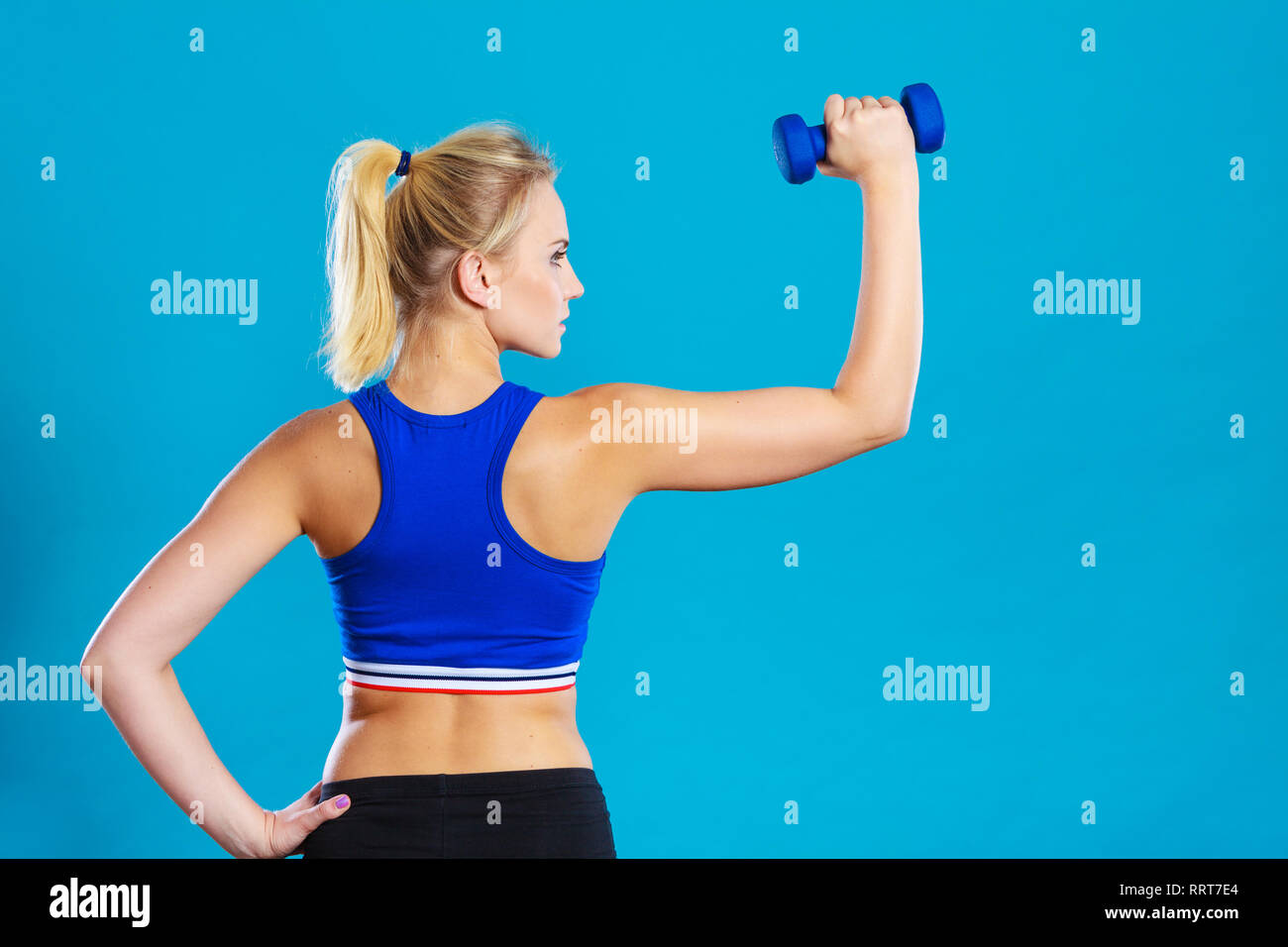 Sporty woman lifting light dumbbells weights. Fit girl exercising building muscles. Fitness and
