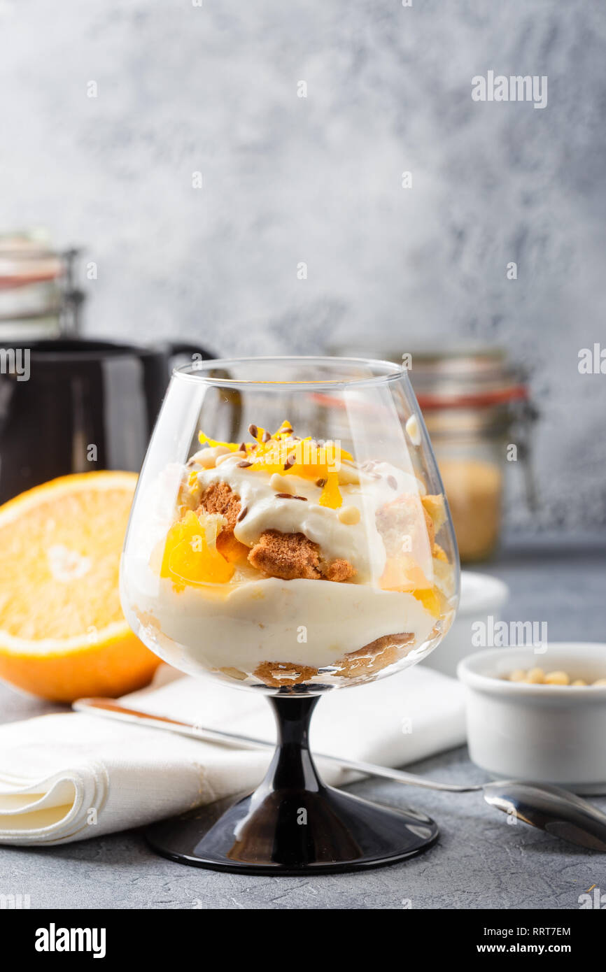 Glass with Healthy homemade layered dessert trifle with orange, biscuit