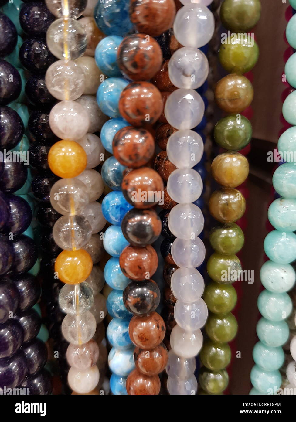 close up vertical background on many beaded necklaces of colorful stones Stock Photo