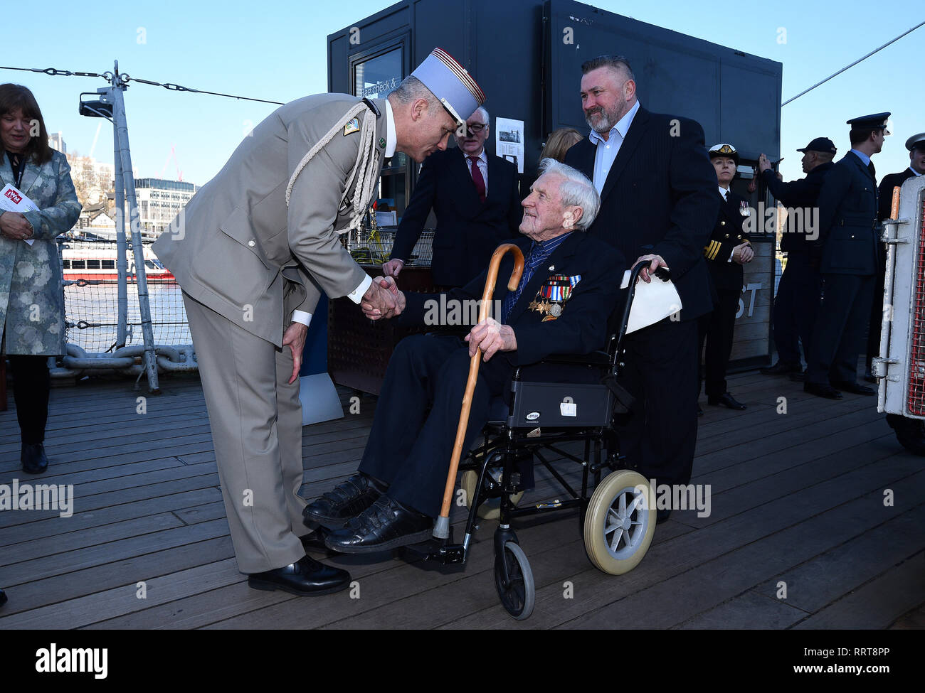 Royal Navy veteran John George Nicholls (centre) is welcomed onboard HMS Belfast in London, where he received an award for helping to liberate Normandy in 1944 during a Legion d'Honneur ceremony on Tuesday. Stock Photo