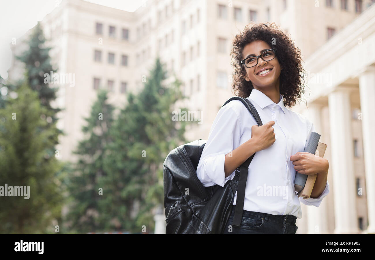 Smiling afro student with backpack and books outdoor Stock Photo