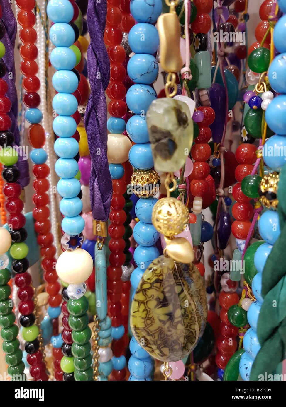 close up vertical background on many beaded necklaces of colorful stones in a store Stock Photo