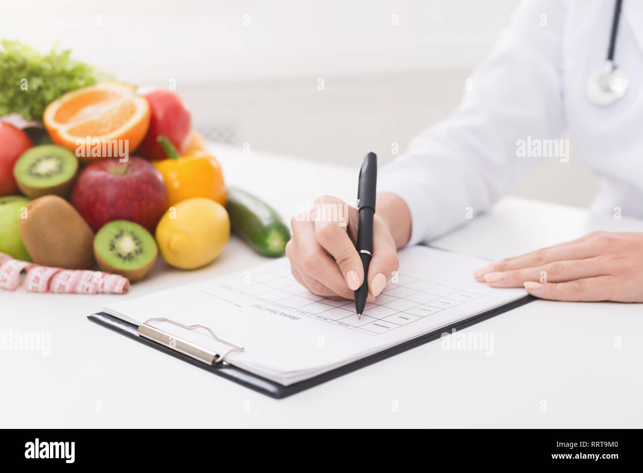 Female nutritionist doctor writing vegetable diet plan Stock Photo