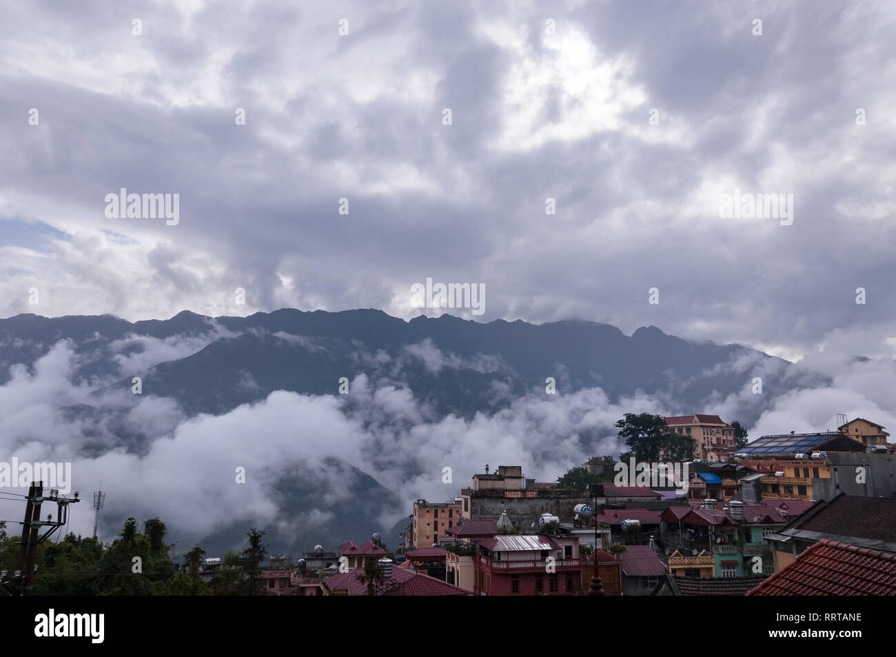 Sa Pa town with Fansipan mountains in background covered in clouds on an overcast afternoon, Vietnam Stock Photo