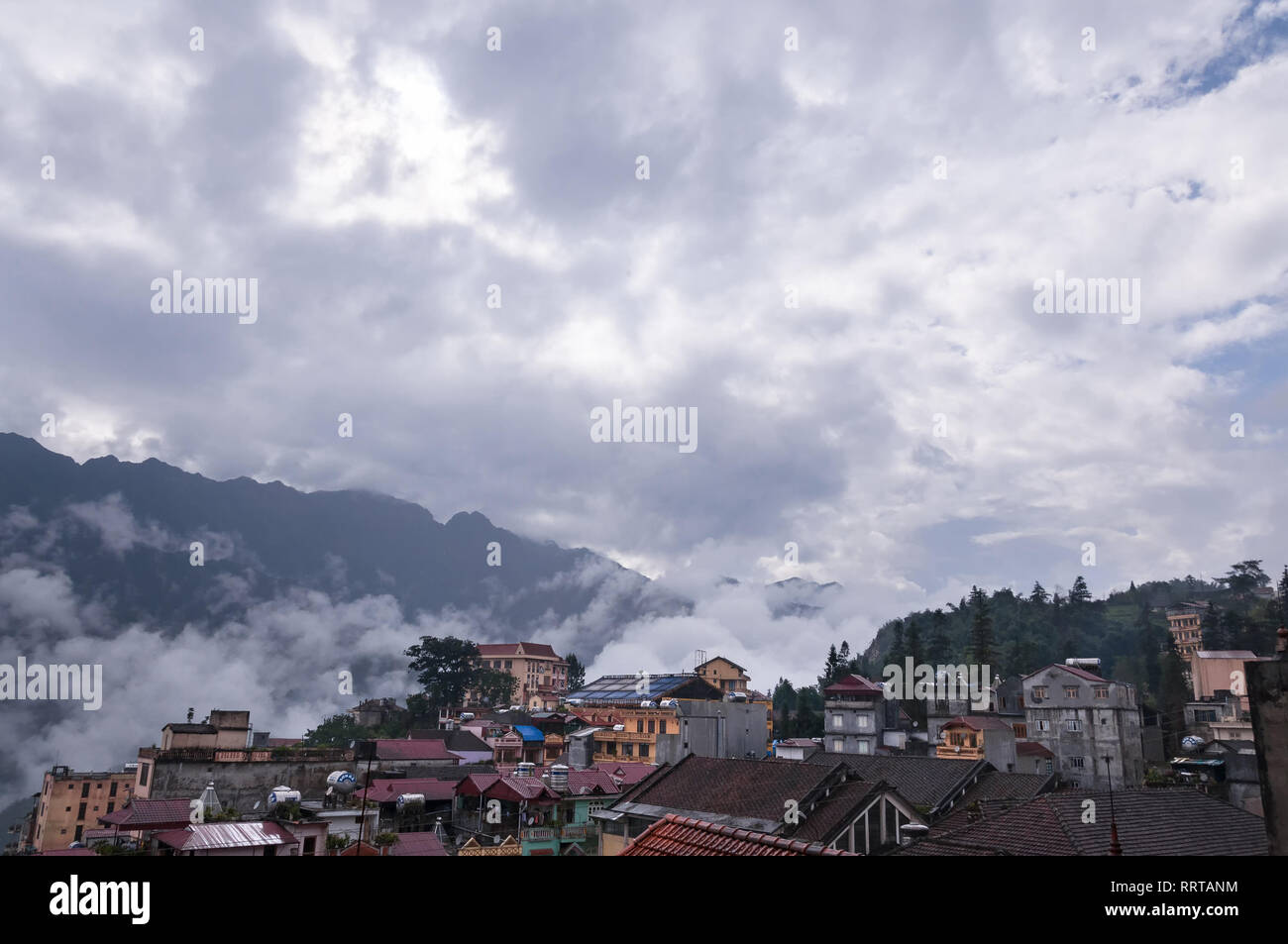 Sa Pa town with Fansipan mountains in background covered in clouds on an overcast afternoon, Vietnam Stock Photo